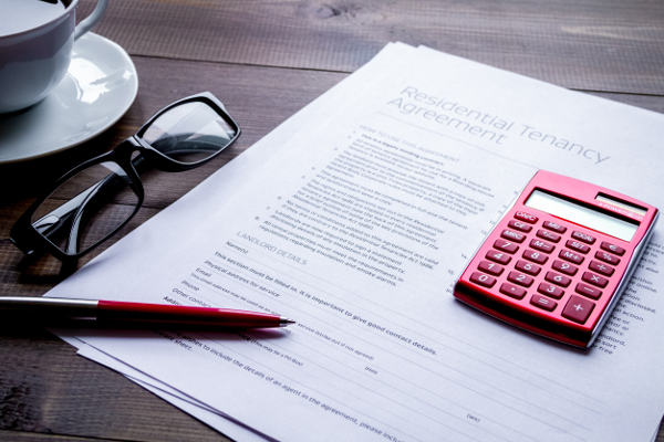 Contract on wooden desk with calculator, pen, glasses