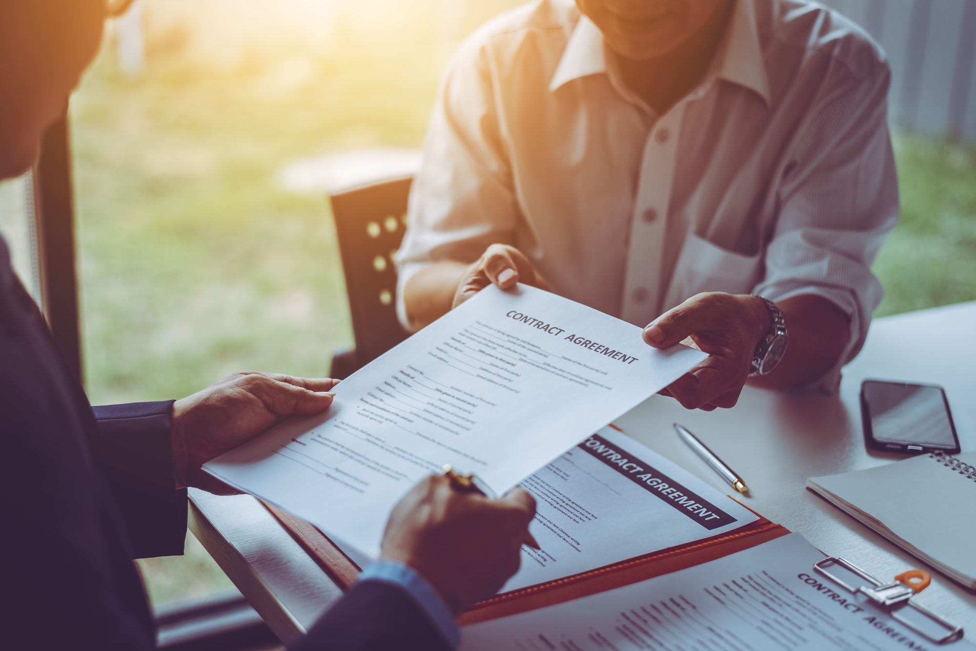 Two middle-age Asian business people reviewing a contract agreement in a meeting room